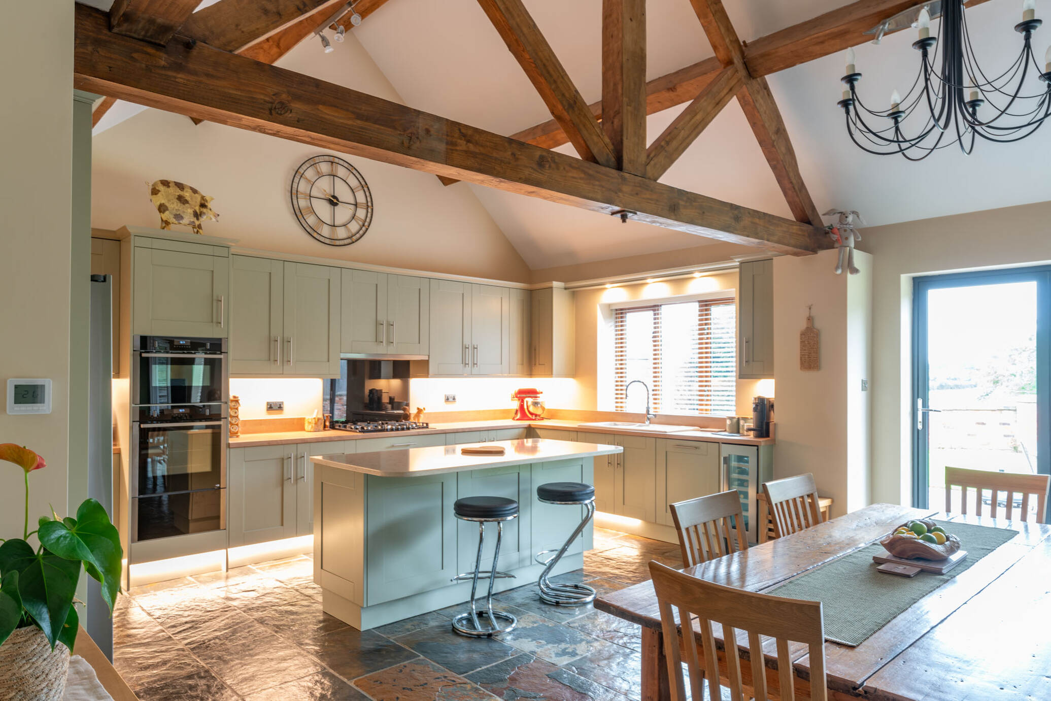 Wood Shaker painted furniture in Sage Grey | Worktops Quartz and Egger wood reproduction in Hamilton Oak | Neff appliances, including Slide & Hide oven, warming drawer and telescopic hood | Slimline wine fridge